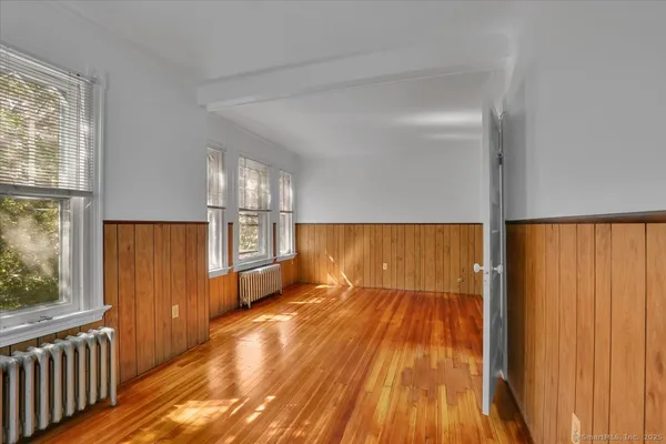 a view of hallway with window and wooden floor