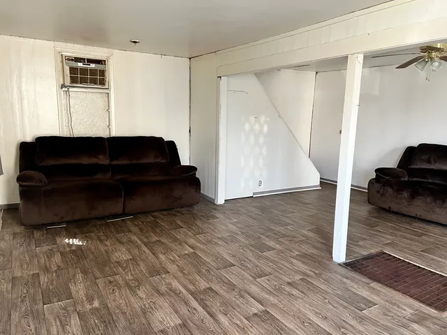 a living room with a couch and a potted plant on a wooden floor