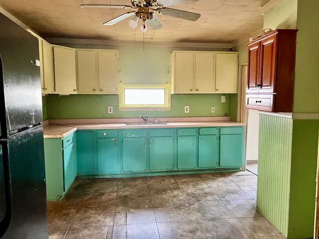 a kitchen with green walls cabinets and a refrigerator