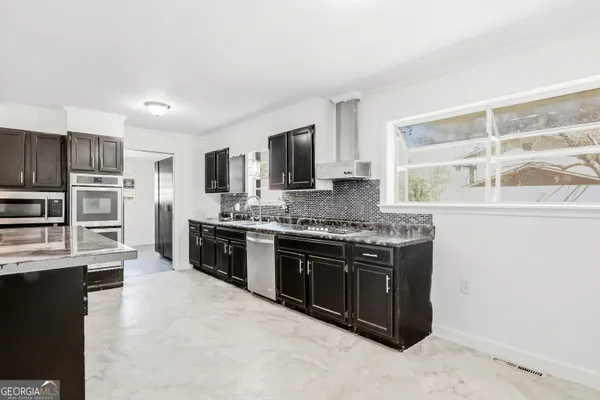 a large kitchen with stainless steel appliances granite countertop a stove a sink dishwasher a refrigerator and a microwave