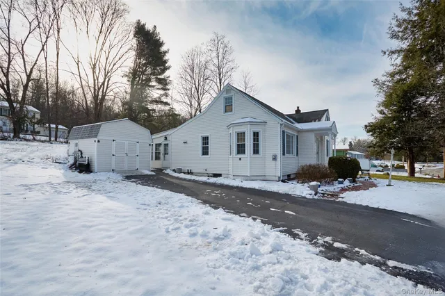 a view of a white house with a large space covered with snow in front of it