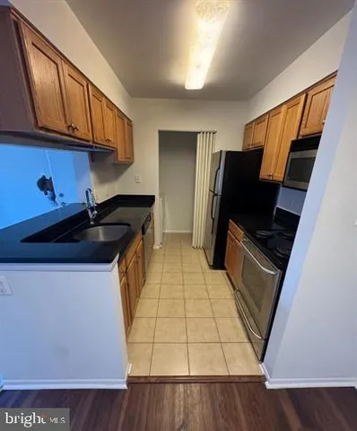 a kitchen with stainless steel appliances a stove a refrigerator a sink and wooden cabinets