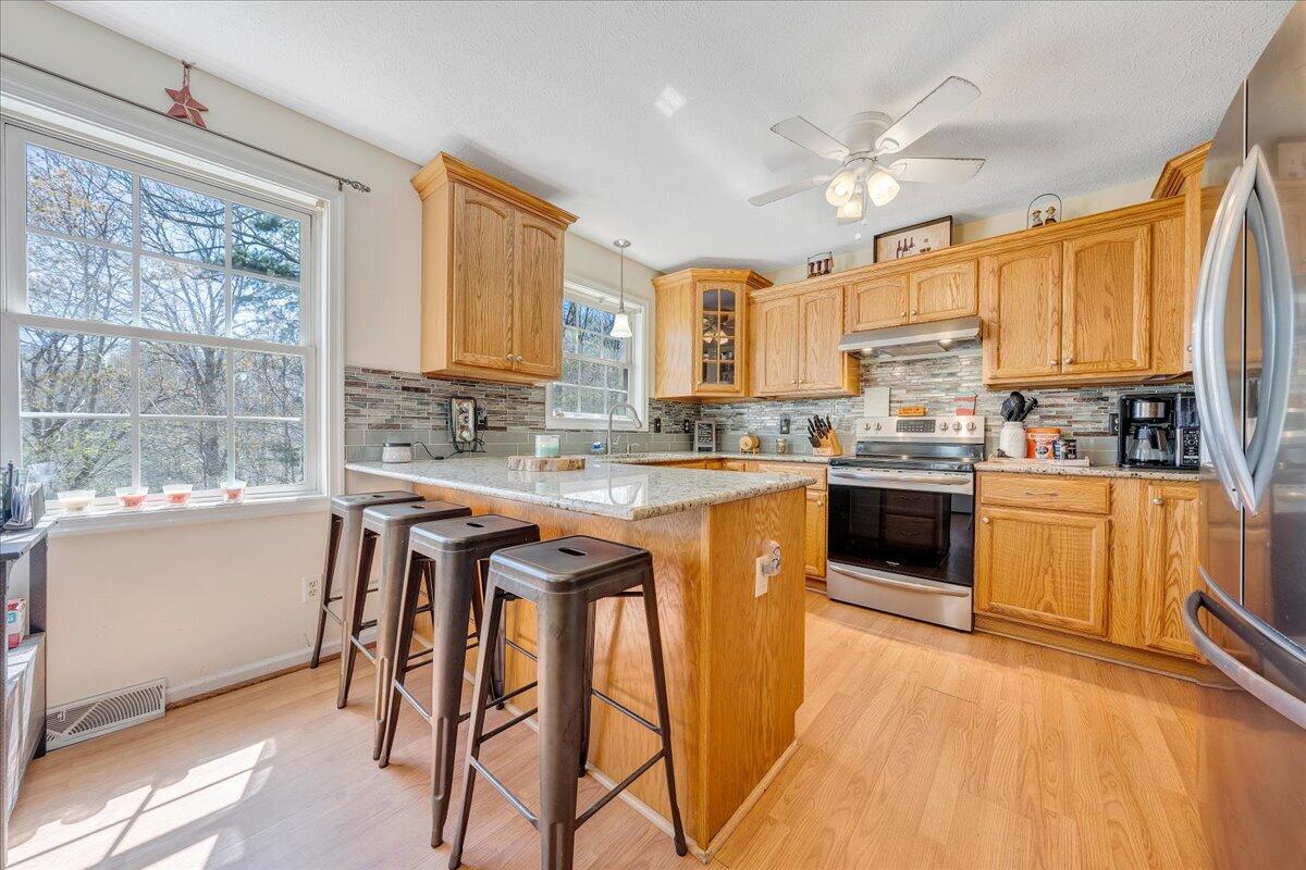 5497 Bethany Road Rustburg, VA 24588 - Photo 8 of 52 a kitchen with stainless steel appliances granite countertop wooden cabinets a sink a stove a dining table and chairs