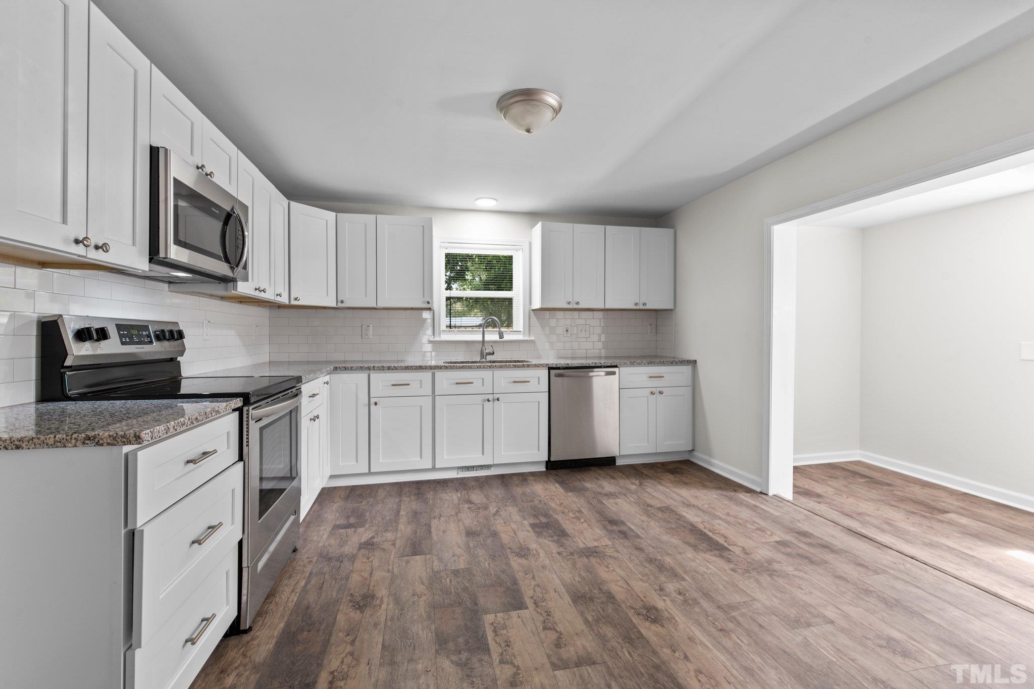 305 West Horton Street Zebulon, NC 27597 - Photo 12 of 29 a kitchen with stainless steel appliances granite countertop a sink cabinets and wooden floor