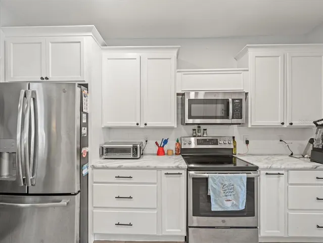a kitchen with white cabinets and stainless steel appliances