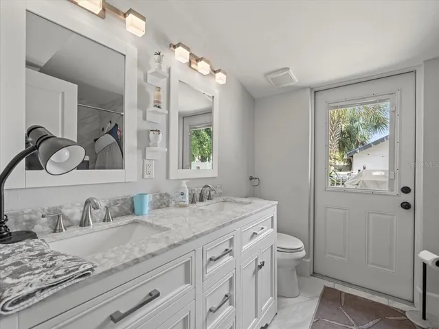 a bathroom with a granite countertop sink mirror and toilet
