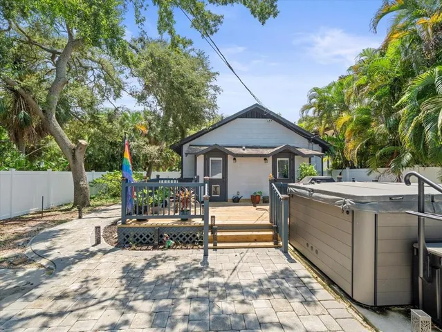 a view of a white house with a large tree and wooden fence