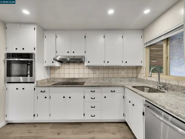 a kitchen with granite countertop a refrigerator and white cabinets
