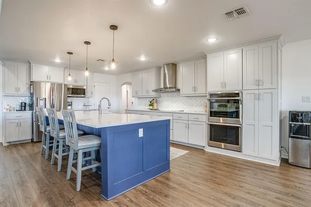 a large kitchen with cabinets wooden floor stainless steel appliances and a counter space