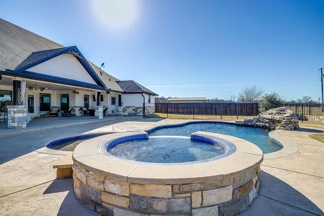 a view of swimming pool with outdoor seating and house in the background
