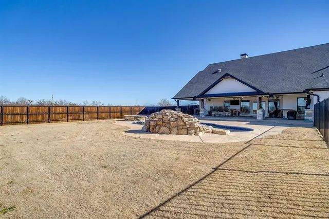 a view of pool with a lawn chairs under an umbrella