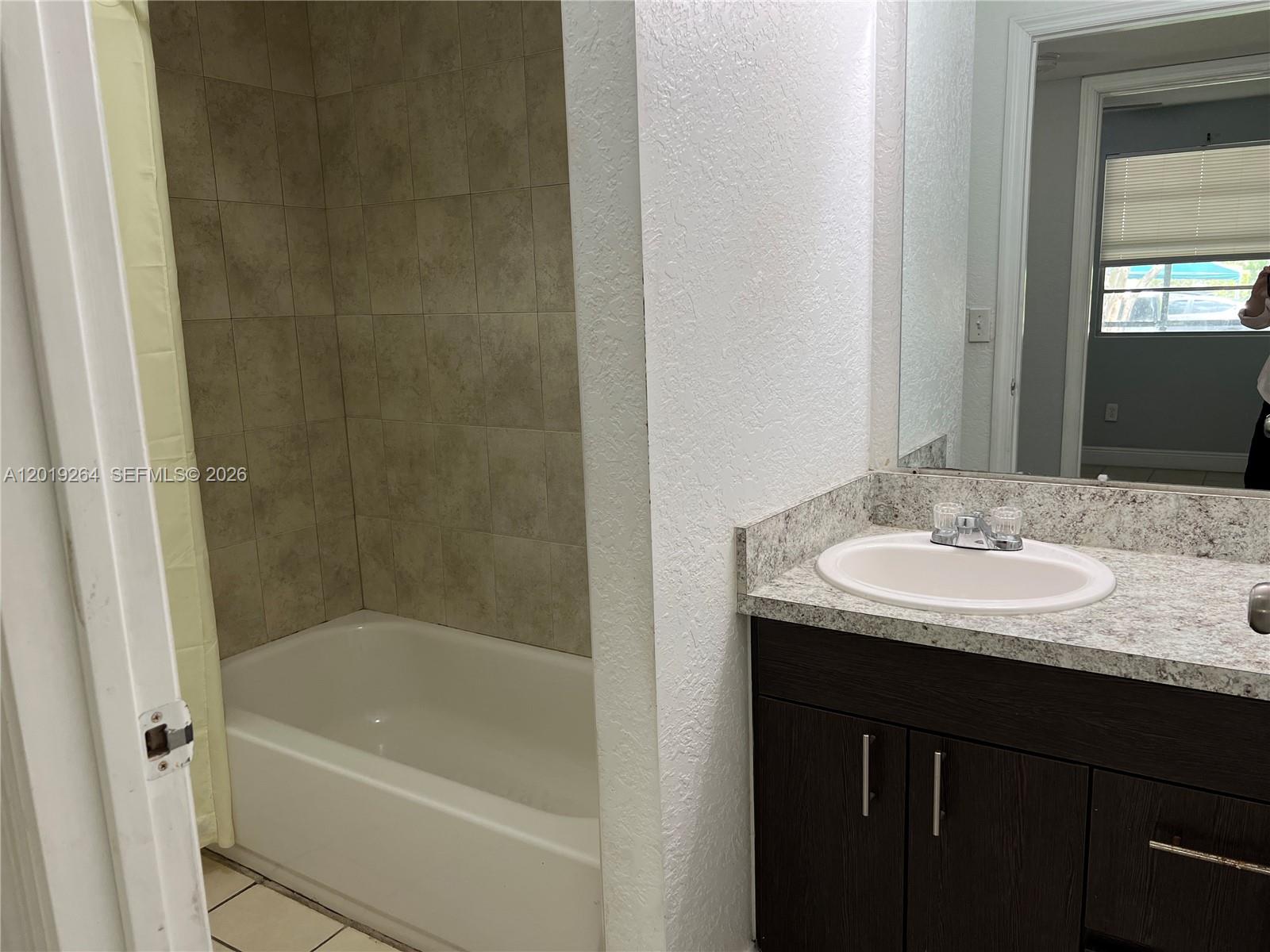 1237 Southwest 46th Avenue, Unit 801 Pompano Beach, FL 33069 - Photo 2 of 8 a bathroom with a granite countertop sink a mirror and a bathtub
