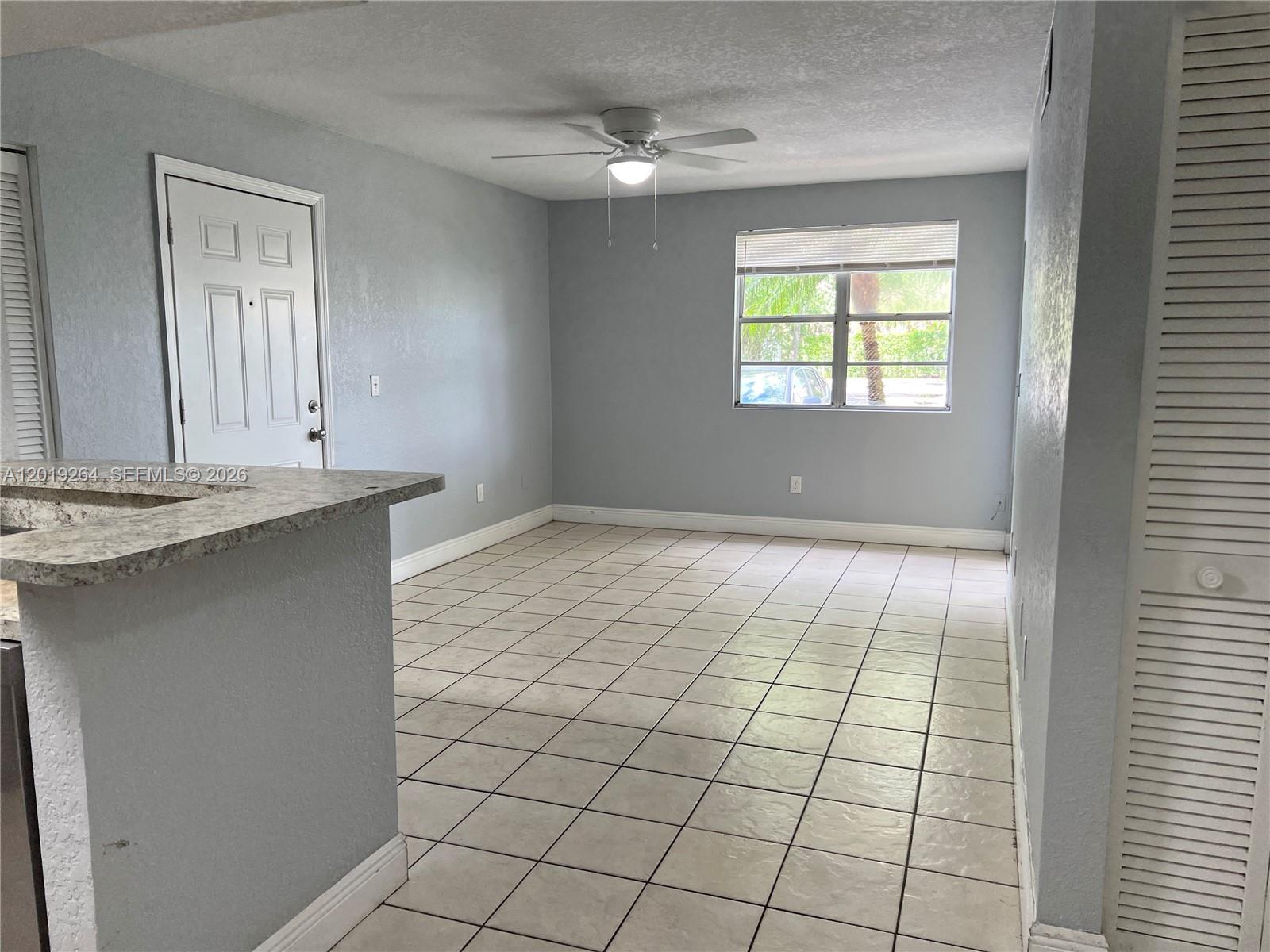 1237 Southwest 46th Avenue, Unit 801 Pompano Beach, FL 33069 - Photo 3 of 8 a view of an empty room with window and chandelier fan