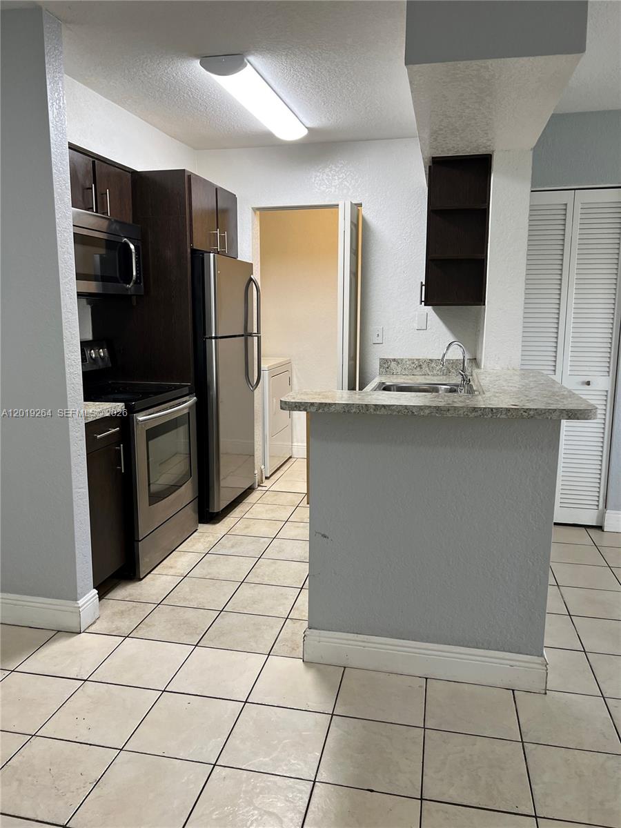 1237 Southwest 46th Avenue, Unit 801 Pompano Beach, FL 33069 - Photo 4 of 8 a kitchen with stainless steel appliances granite countertop a refrigerator and a sink