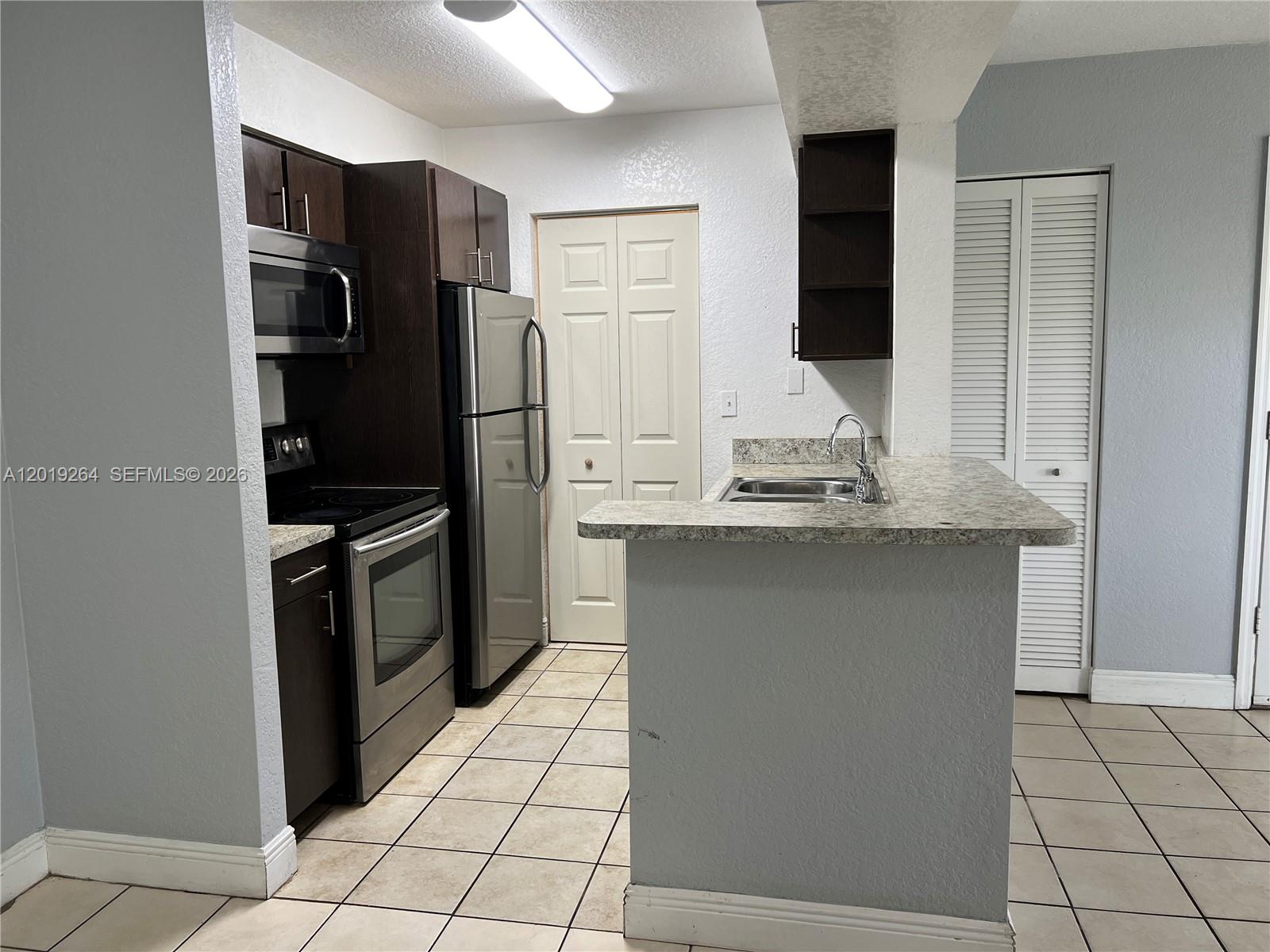 1237 Southwest 46th Avenue, Unit 801 Pompano Beach, FL 33069 - Photo 5 of 8 a kitchen with stainless steel appliances kitchen island granite countertop a refrigerator and a stove