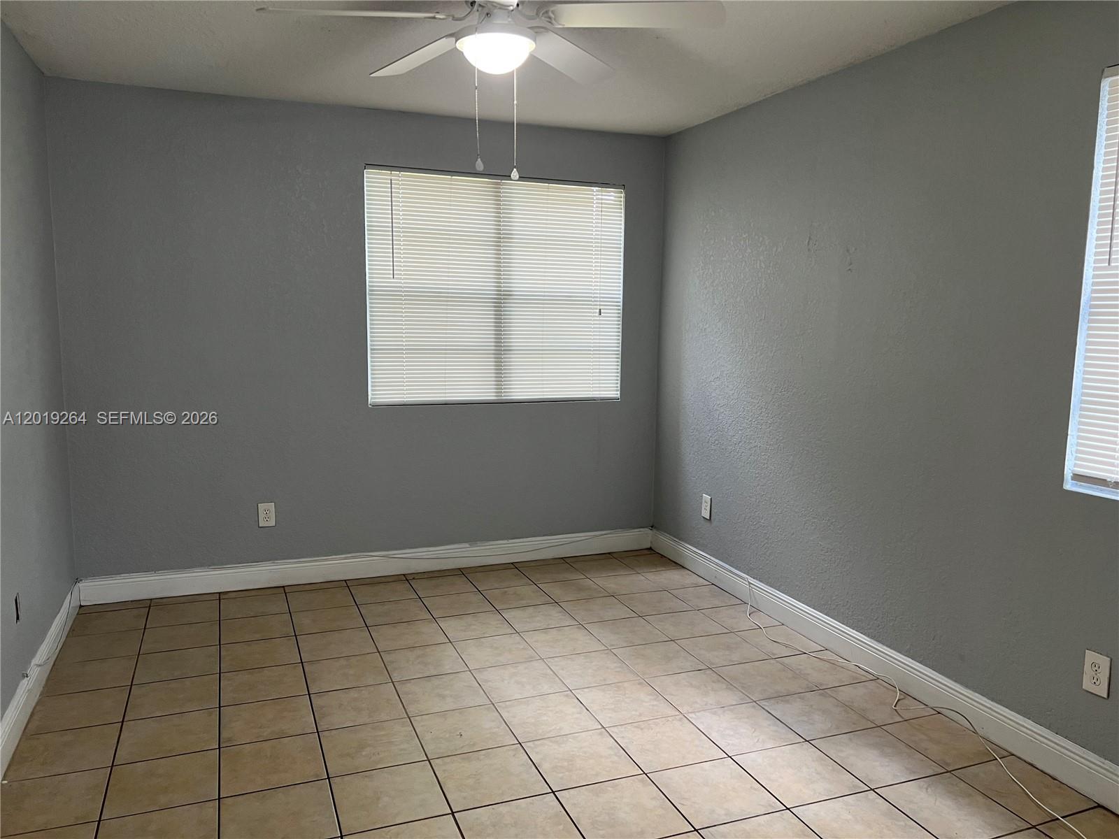 1237 Southwest 46th Avenue, Unit 801 Pompano Beach, FL 33069 - Photo 7 of 8 an empty room with chandelier fan and window