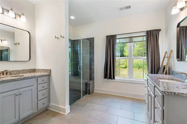 a bathroom with a granite countertop sink a mirror and shower