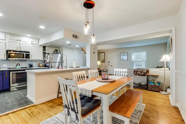 a kitchen with stainless steel appliances granite countertop a stove top oven a sink dishwasher a dining table and chairs with wooden floor