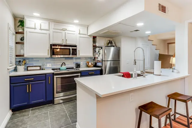 a kitchen with stainless steel appliances a sink stove refrigerator and cabinets