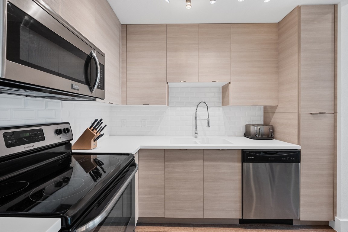 You will enjoy your time in this kitchen which has contemporary fixtures, a subway tile backsplash, Corian countertops, stainless steel appliances and sleek cabinetry.
