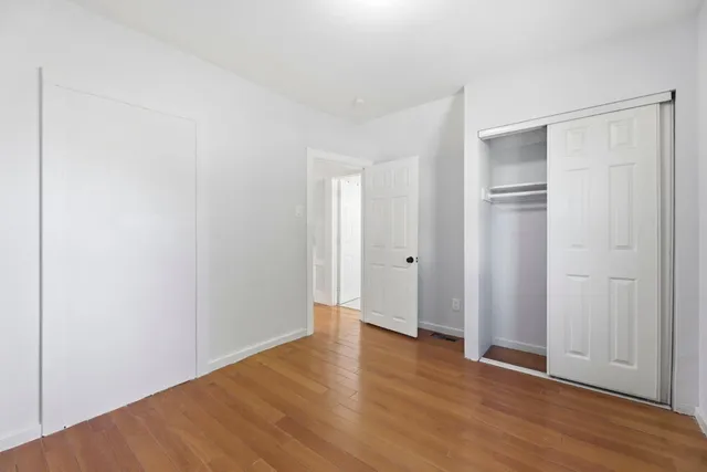 a view of an empty room with closet and wooden floor