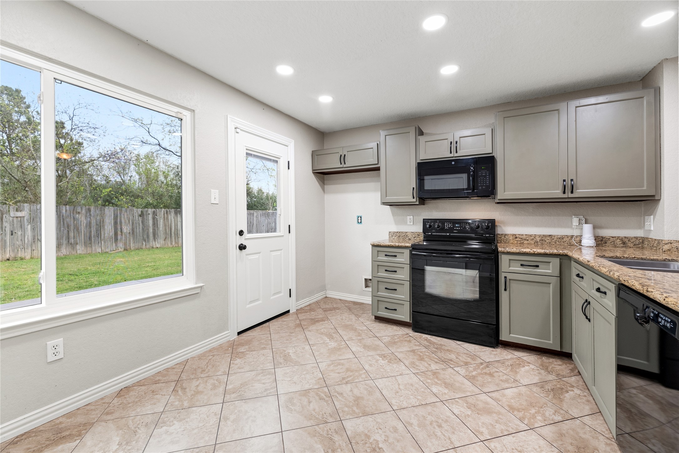 24006 Lazy Kay Lane Hockley, TX 77447 - Photo 7 of 21 Bright kitchen and breakfast area with modern cabinetry, granite countertops, and tile flooring. The large new windows highlight the beautiful greenspace behind the home. No back neighbors!