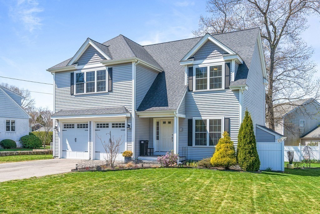 a front view of a house with a yard potted plants and large tree