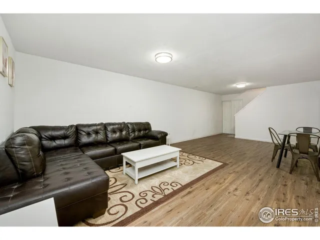 a living room with furniture and a dining table with wooden floor