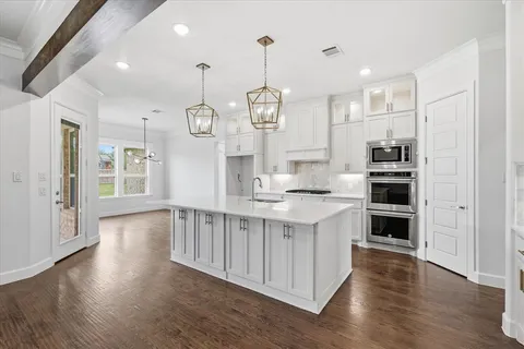 a kitchen with stainless steel appliances granite countertop a kitchen island hardwood floor and a sink