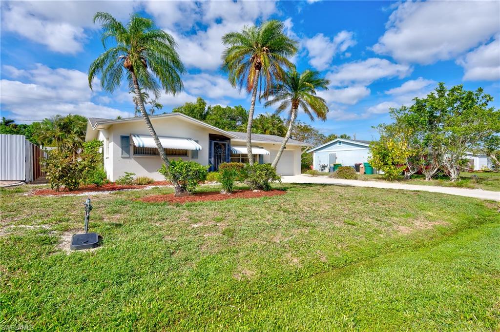 4815 Cortez Circle Naples, FL 34112 - Photo 3 of 31 a backyard of a house with table and chairs under an umbrella