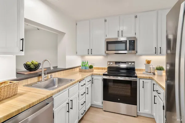 a kitchen with granite countertop white cabinets white stainless steel appliances and a sink