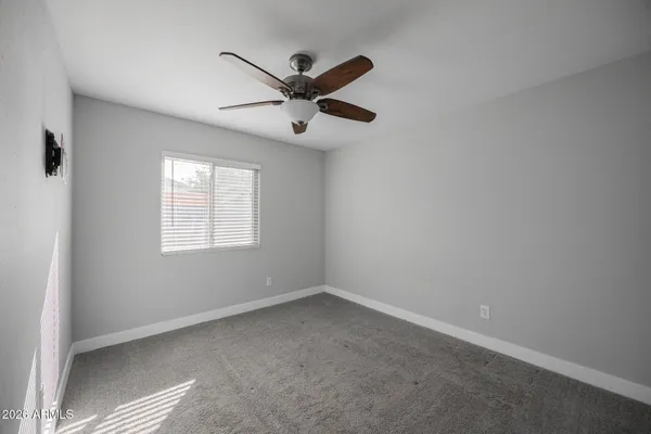 an empty room with windows and fan