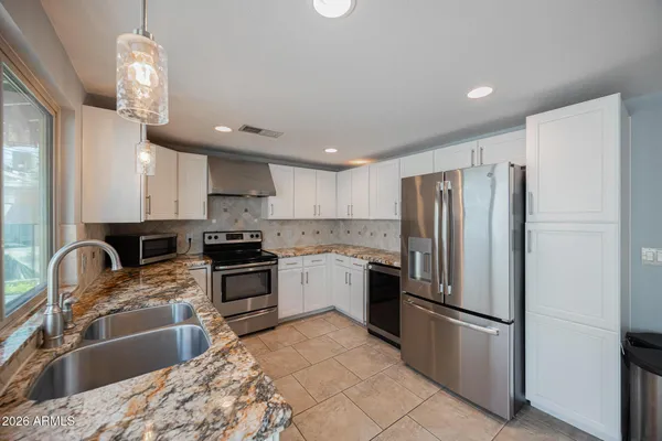 a kitchen with stainless steel appliances granite countertop a refrigerator a stove a sink and a microwave