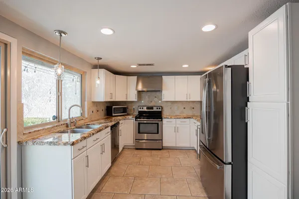 a large kitchen with stainless steel appliances granite countertop a refrigerator and a stove top oven