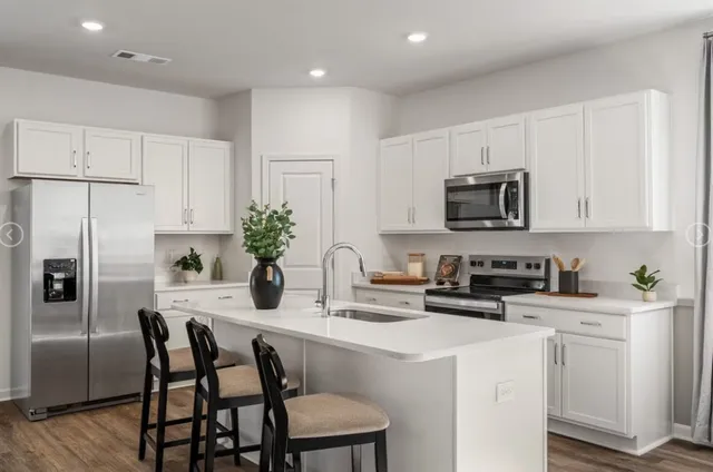 a kitchen with kitchen island granite countertop white cabinets and stainless steel appliances