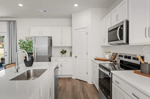 a kitchen with a sink white cabinets and stainless steel appliances