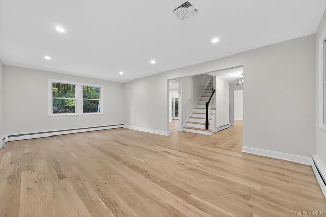 a view of an empty room with a window and wooden floor