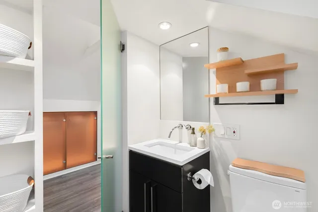 a living room with couches a coffee table and kitchen view with wooden floor