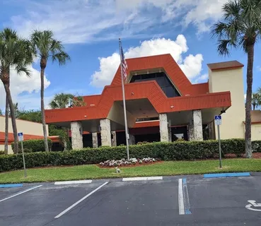 a view of a house with a yard and palm trees