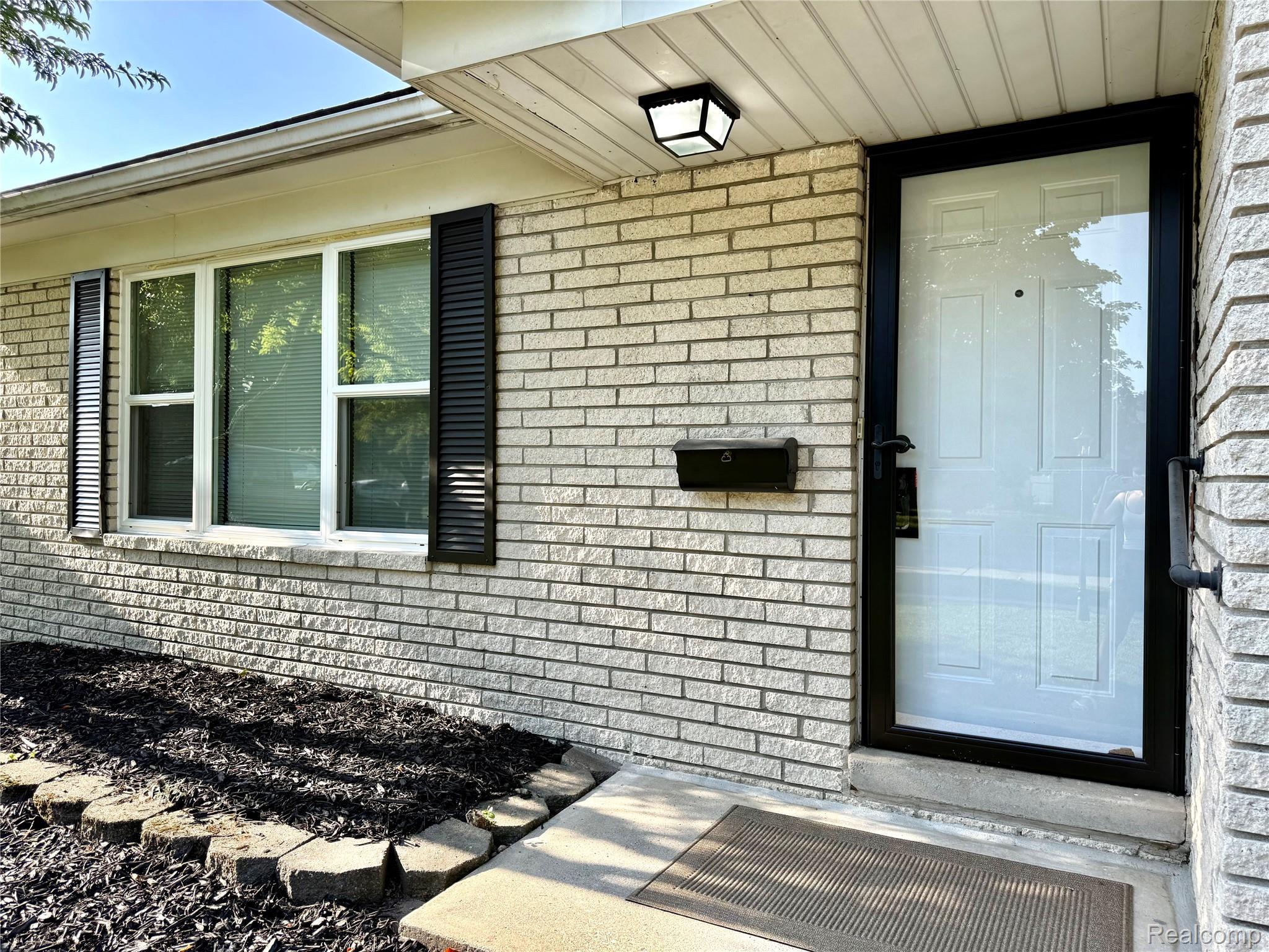 39909 Lynn Street Canton, MI 48187 - Photo 2 of 45 White brick exterior with black shutters and a black storm door