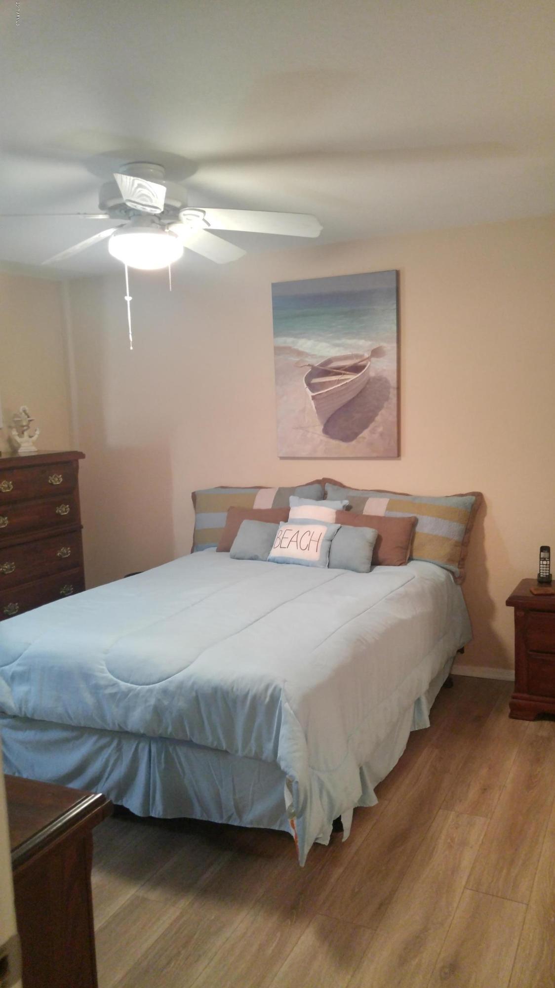 1340 North Recker Road, Unit 219 Mesa, AZ 85205 - Photo 24 of 41 a bedroom with a bed and lamp with wooden floor