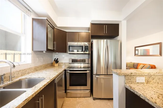 a kitchen with stainless steel appliances granite countertop a sink a stove and a refrigerator