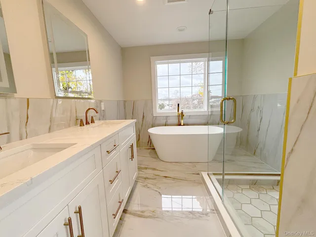 a bathroom with a double vanity sink a mirror and a bathtub
