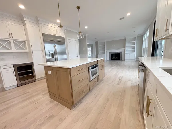 a kitchen with kitchen island a sink a counter top space stainless steel appliances and a fireplace