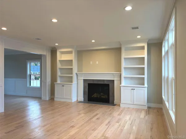 an empty room with wooden floor fireplace and windows