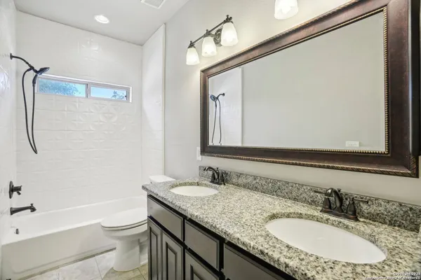 a bathroom with a granite countertop tub sink and mirror