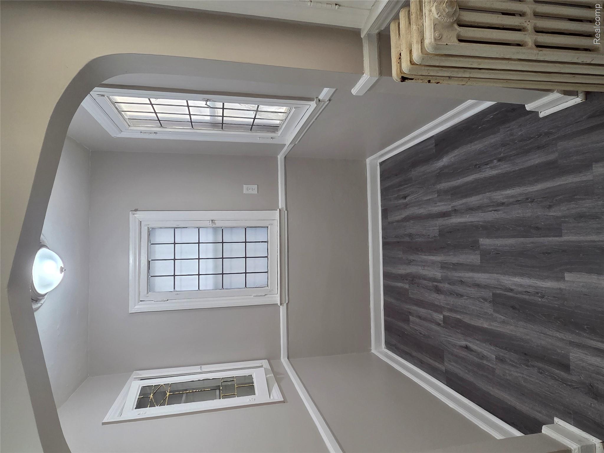 5274 Nottingham Road Detroit, MI 48224 - Photo 12 of 18 Empty room with arched walkways, radiator, and dark wood-style flooring