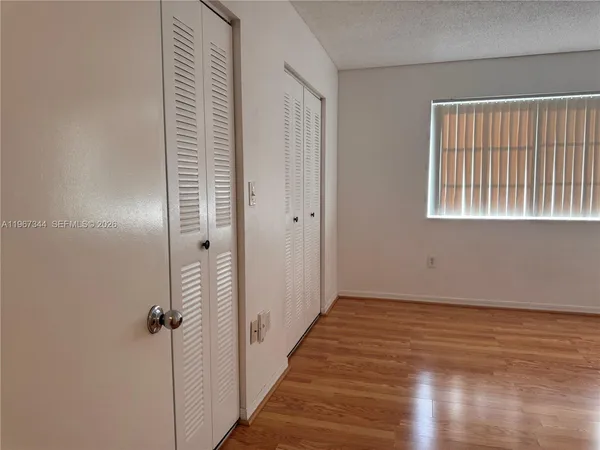 a view of a hallway with wooden floor and a bathroom