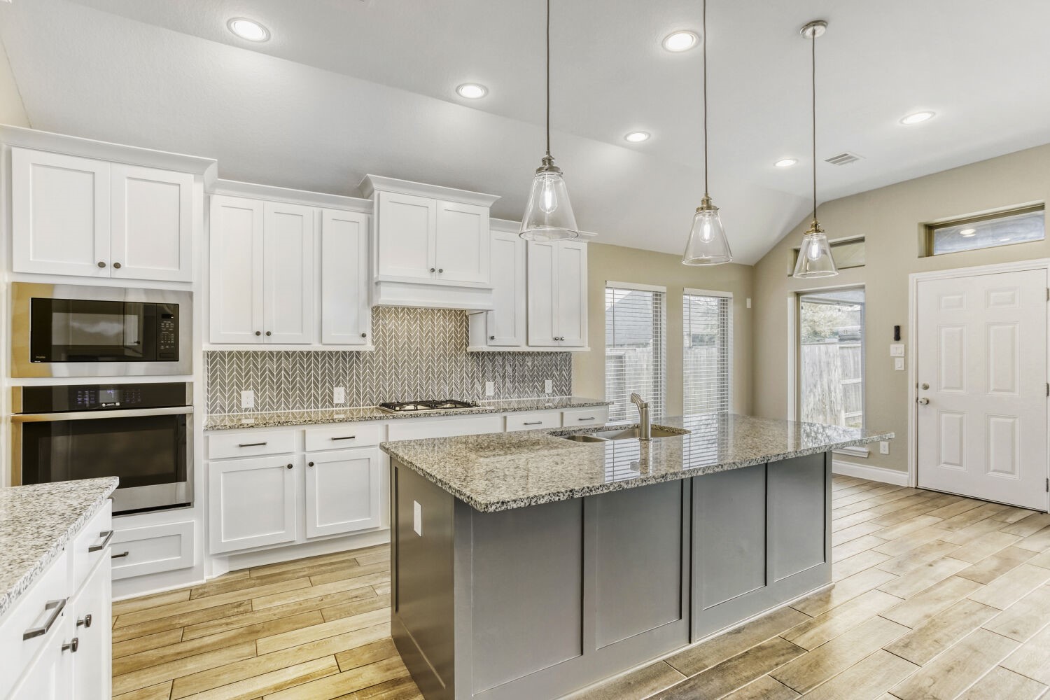 9219 Eckert Road Iowa Colony, TX 77583 - Photo 15 of 26 The island kitchen features stainless steel appliances including a gas cooktop, granite countertops, and a designer chevron tile backsplash.