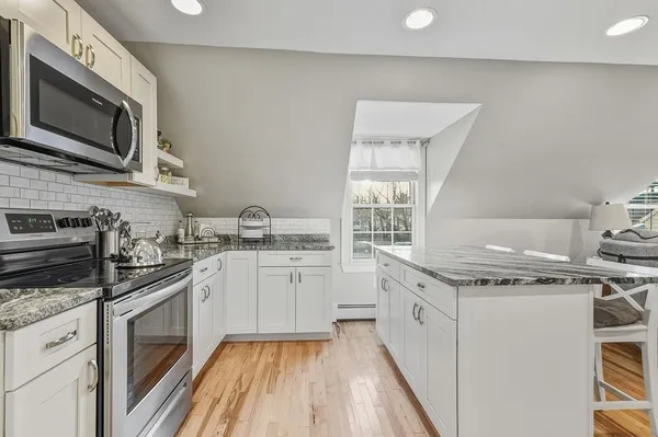 a kitchen with stainless steel appliances granite countertop a stove a sink and a microwave